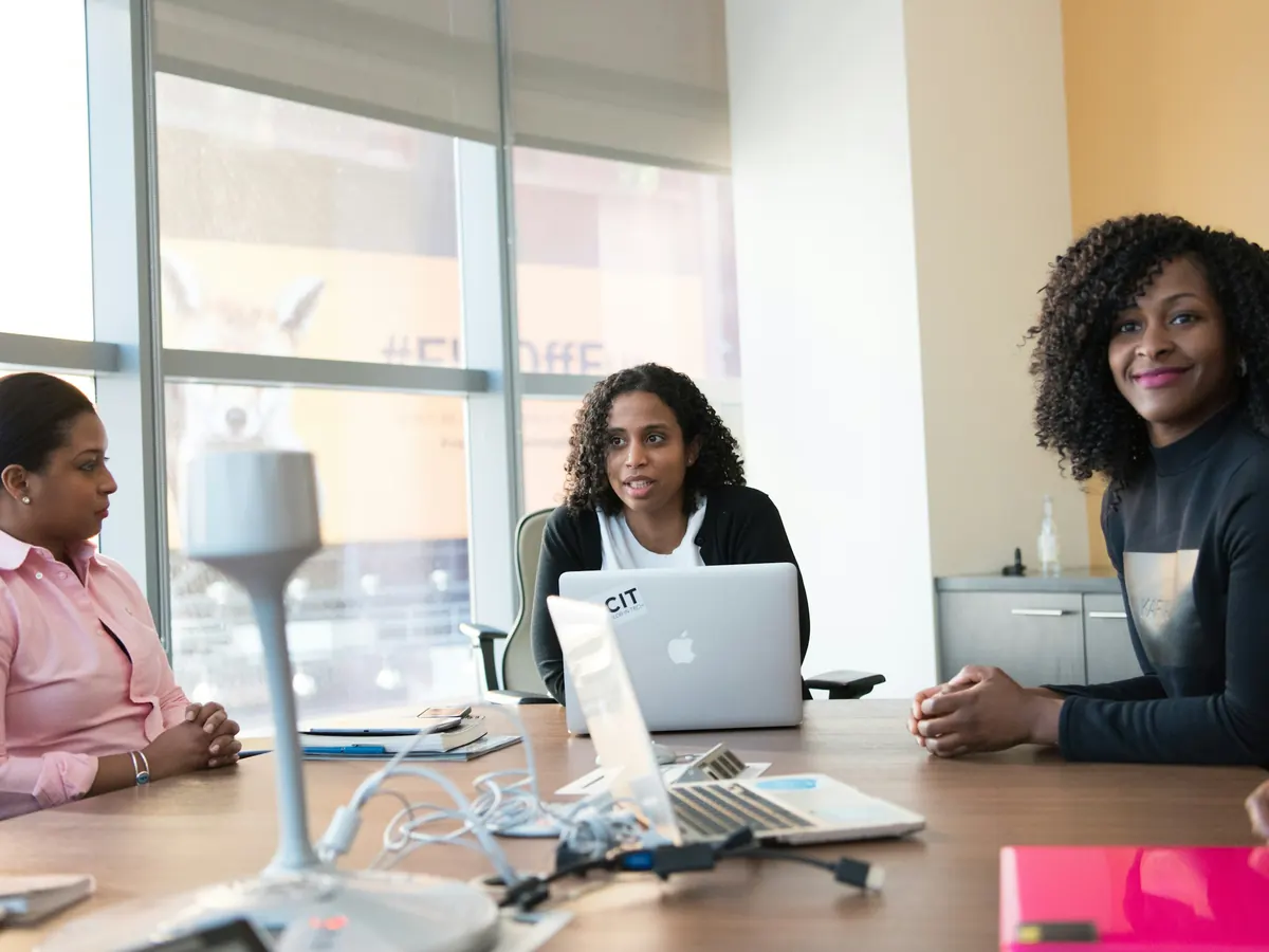 Three colleagues working together at a table with laptops
