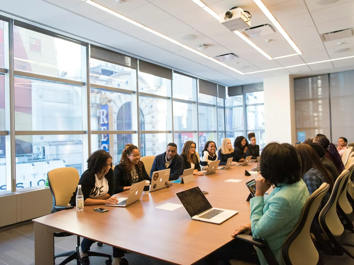 Team meeting around a long table with laptops in a bright office